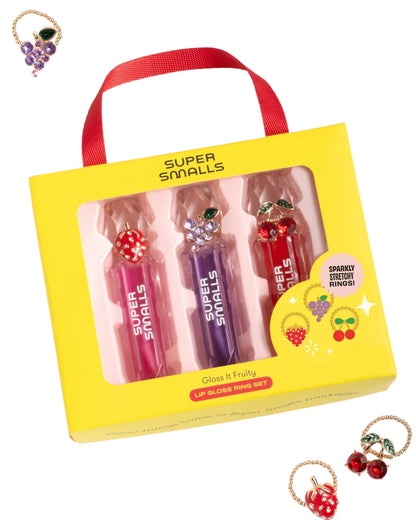 The Super Smalls Gloss it Fruity Lip Gloss Ring Set includes a trio of fruity lip glosses in pink, purple, and red tubes plus three colorful rings, shown both inside and outside the packaging.