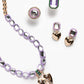 The Super Smalls Lavender Haze Mega Jewelry Set features a purple necklace with gold beads and a heart pendant, a green-bordered ring, plus matching heart-shaped and hexagonal earrings.