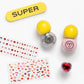 The Paint it Heartfelt Mini Nail Kit by Super Smalls features a yellow “SUPER” nail file, two glitter polishes, decorative and heart stickers, gem stickers, and a heart-shaped ring—all arranged on a white background.