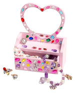 The Super Smalls Mini Vanity Gemify Craft Kit features a pink, heart-shaped jewelry box with gem stickers, filled with beaded necklaces, rings, and earrings—perfect for storing your jeweled creations.
