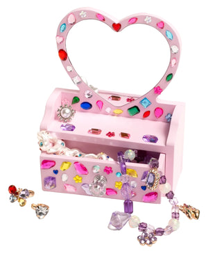 The Super Smalls Mini Vanity Gemify Craft Kit features a pink, heart-shaped jewelry box with gem stickers, filled with beaded necklaces, rings, and earrings—perfect for storing your jeweled creations.