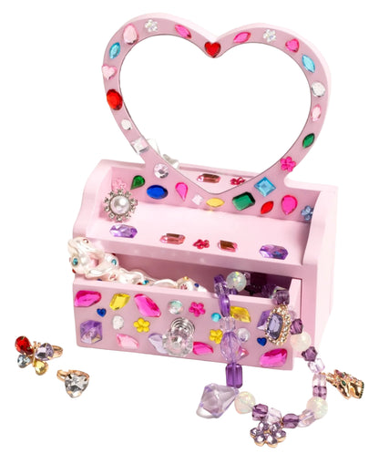 The Super Smalls Mini Vanity Gemify Craft Kit features a pink, heart-shaped jewelry box with gem stickers, filled with beaded necklaces, rings, and earrings—perfect for storing your jeweled creations.