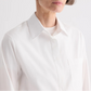 A person wearing the TWP Cowboy Update Shirt, a white collared poplin shirt, shown from shoulders to chest against a plain background.