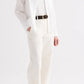 Wearing the TWP Cowboy Update Shirt, a person stands hands in pockets against a plain background, paired with a white t-shirt, white pants, black belt, and brown sandals.