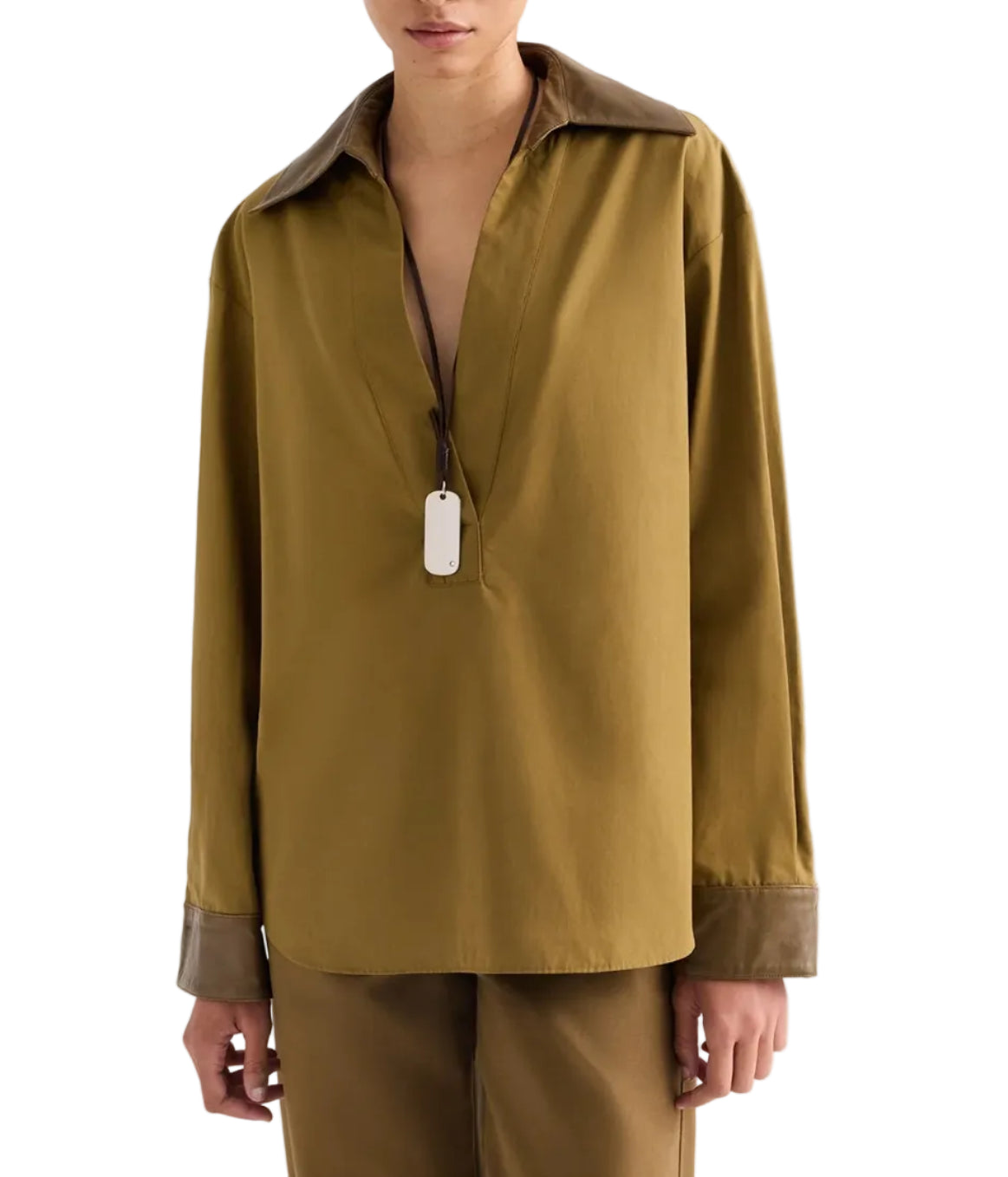 TWP A Case of You Shirt: an olive green cotton long-sleeved pullover with a deep V-neck, contrasting dark brown leather collar and cuffs, and a silver dog tag pendant on a thin cord.