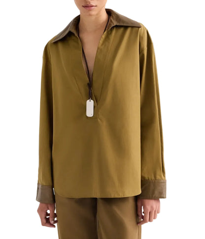 TWP A Case of You Shirt: an olive green cotton long-sleeved pullover with a deep V-neck, contrasting dark brown leather collar and cuffs, and a silver dog tag pendant on a thin cord.