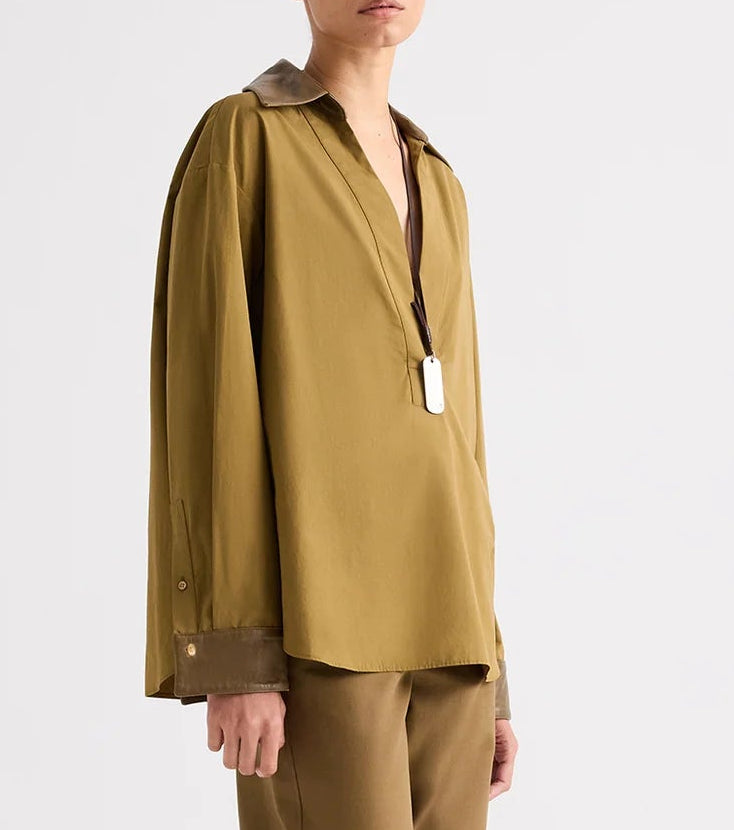 A Case of You Shirt: olive green long-sleeved kangaroo cotton pullover with a deep V-neck, contrasting leather collar and cuffs, and a silver dog tag pendant.