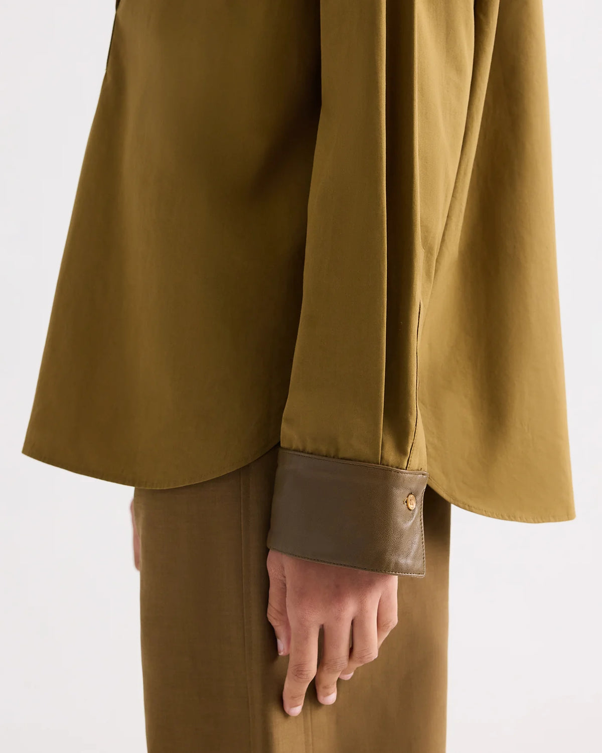 TWP A Case of You Shirt in olive green cotton, featuring a long-sleeved kangaroo silhouette with a contrasting dark brown leather collar and cuffs.