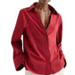 Model wearing the Deep V Relaxed Shirt by TWP in Karanda Red, crafted from Italian superfine cotton. The oversized button-down features an open collar and long sleeves, paired here with light-colored pants. Hands are in pockets and face is partially out of frame.