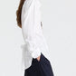Side view of a person wearing The Night We Met Shirt in superfine cotton with a self-tie waist detail at the lower back, paired with navy trousers.