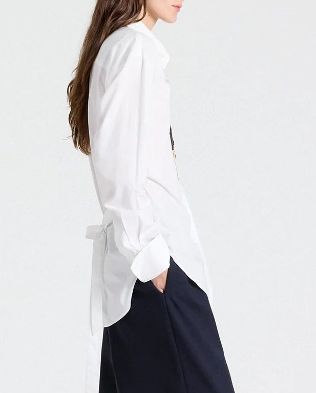 Side view of a person wearing The Night We Met Shirt in superfine cotton with a self-tie waist detail at the lower back, paired with navy trousers.