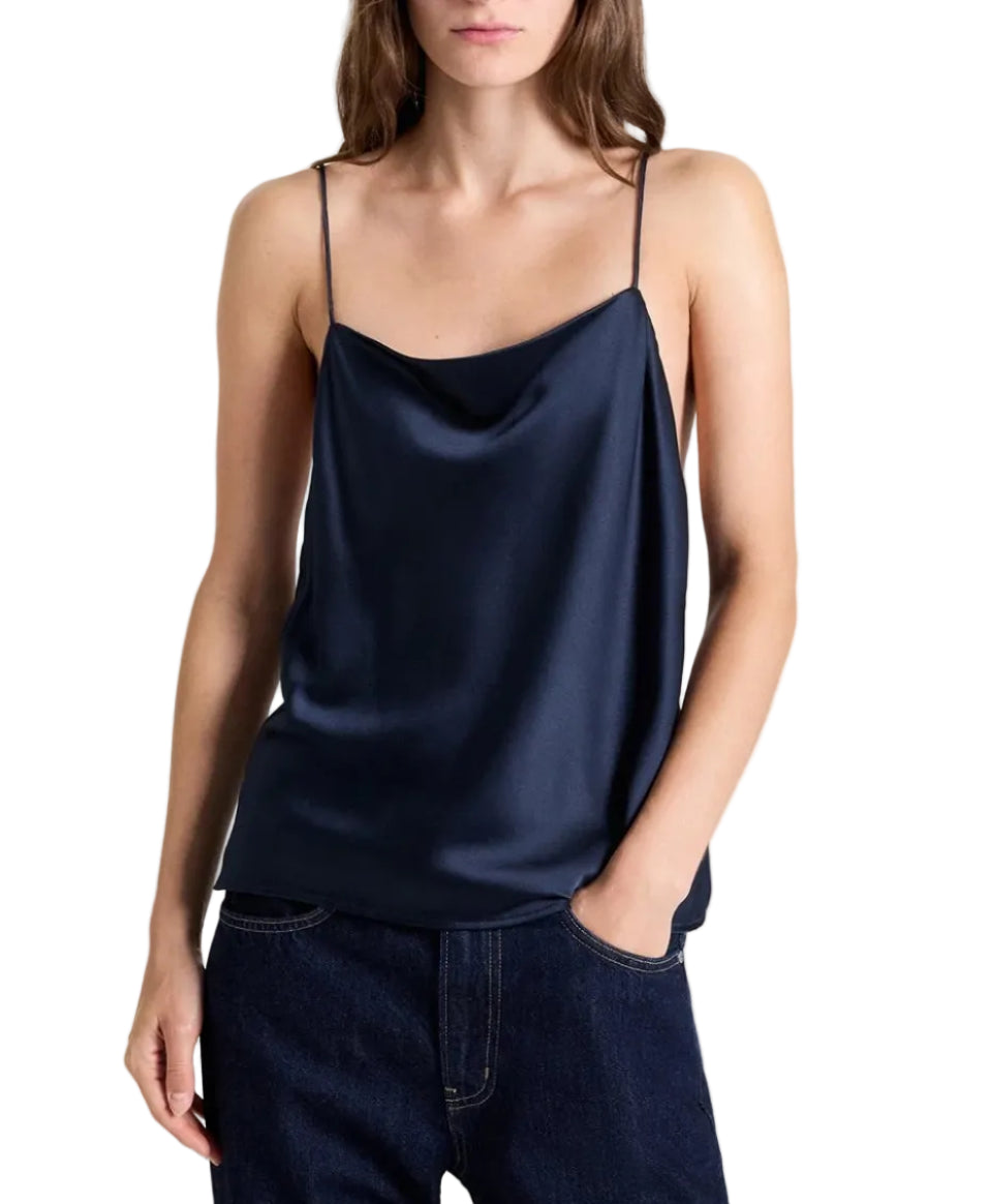 A navy blue crepe back silk satin Sari Tank by TWP featuring a draped cowl neckline and spaghetti straps, worn with dark blue jeans.