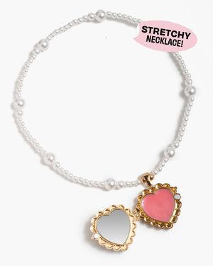 A stretchy faux-pearl necklace by Super Smalls with a gold scalloped heart-shaped locket—one side pink, the other a mirror—inspired by the Sweetheart Surprise Lipgloss Locket.