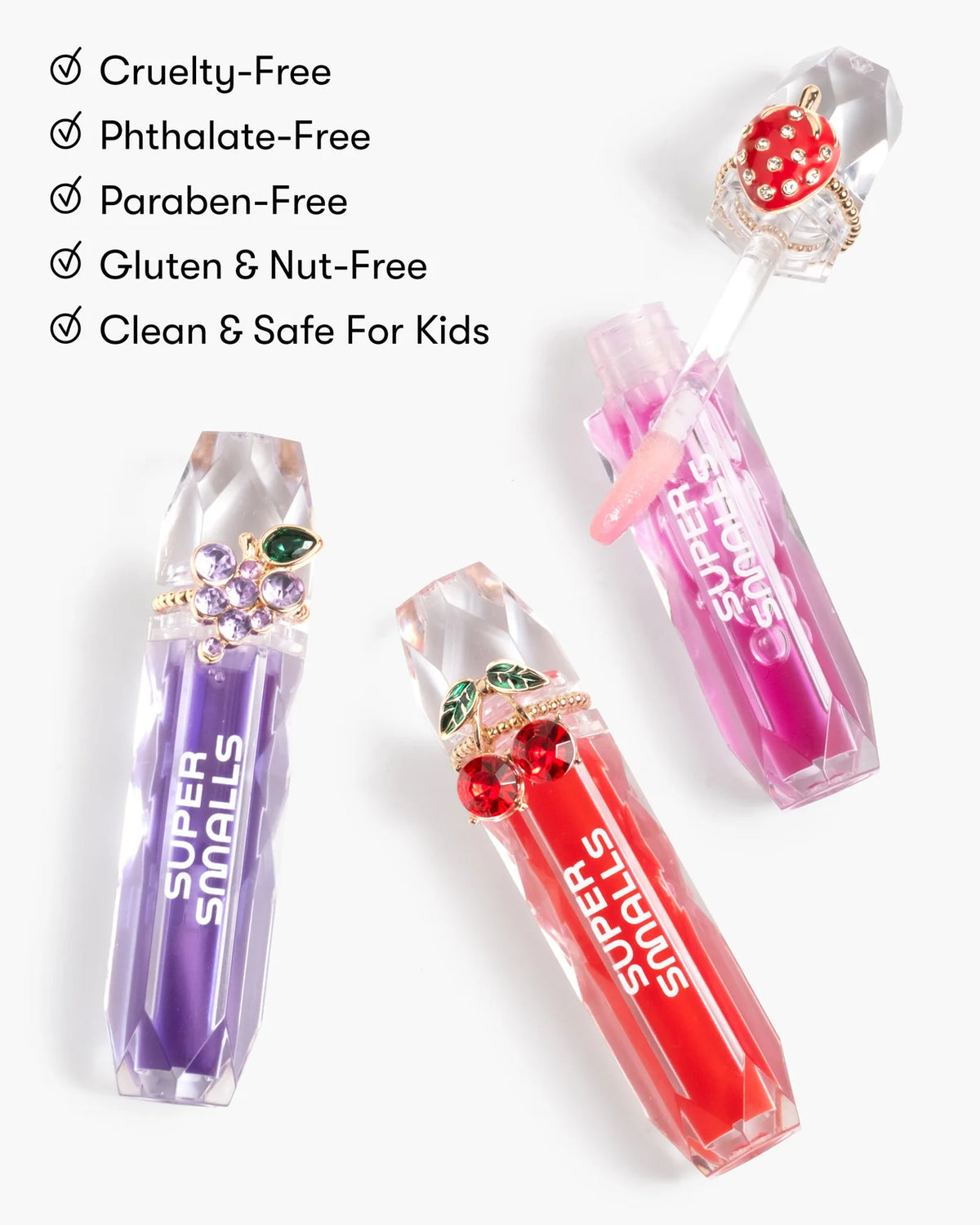 Three jewel-inspired lip glosses from Super Smalls’ Gloss it Rainbow Lip Gloss Ring Set, in purple, pink, and red—cruelty-free, phthalate-free, paraben-free, gluten- and nut-free, and safe for kids.
