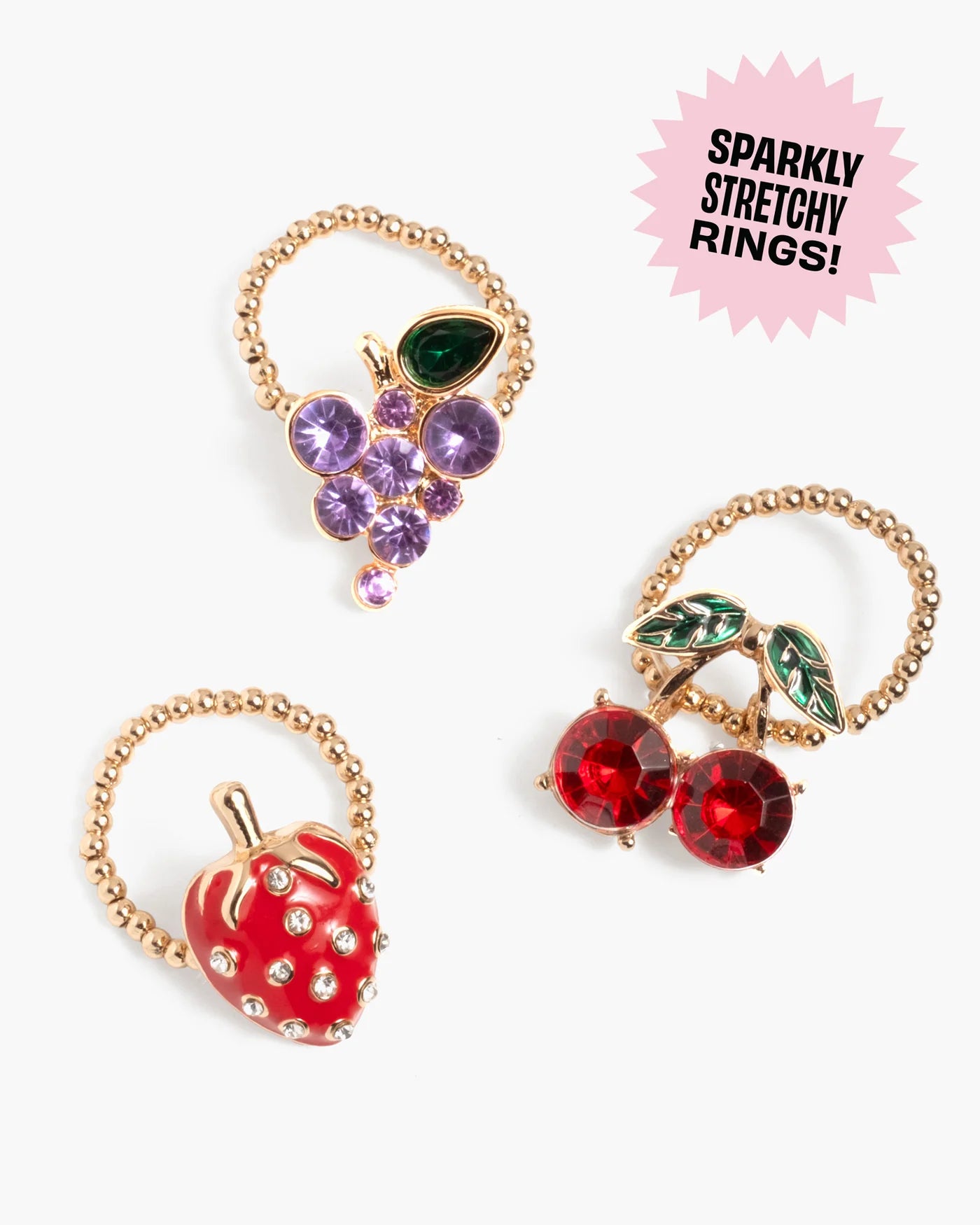 Three gold beaded stretchy rings with grape, cherry, and strawberry designs from Super Smalls’ Gloss it Fruity Lip Gloss Ring Set are displayed on a white background. The label reads “Sparkly Stretchy Rings!”.