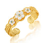 The Villandry Fleur Scalloped Cuff by Juliska Capucine De Wulf features a gold hammered texture, white enamel flowers with blue centers, and intricate leaf details.