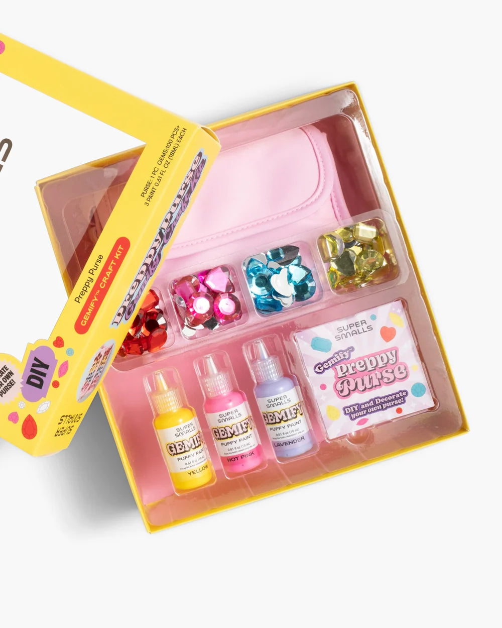 Introducing the Super Smalls Preppy Purse Gemify™ Craft Kit—a cheerful yellow box featuring a pink purse, bottles of colorful gem glue, assorted large plastic gems, and an exclusive “Preppy Purse” label. Perfect for anyone who loves creative projects and wants to design their own stylish accessory!.