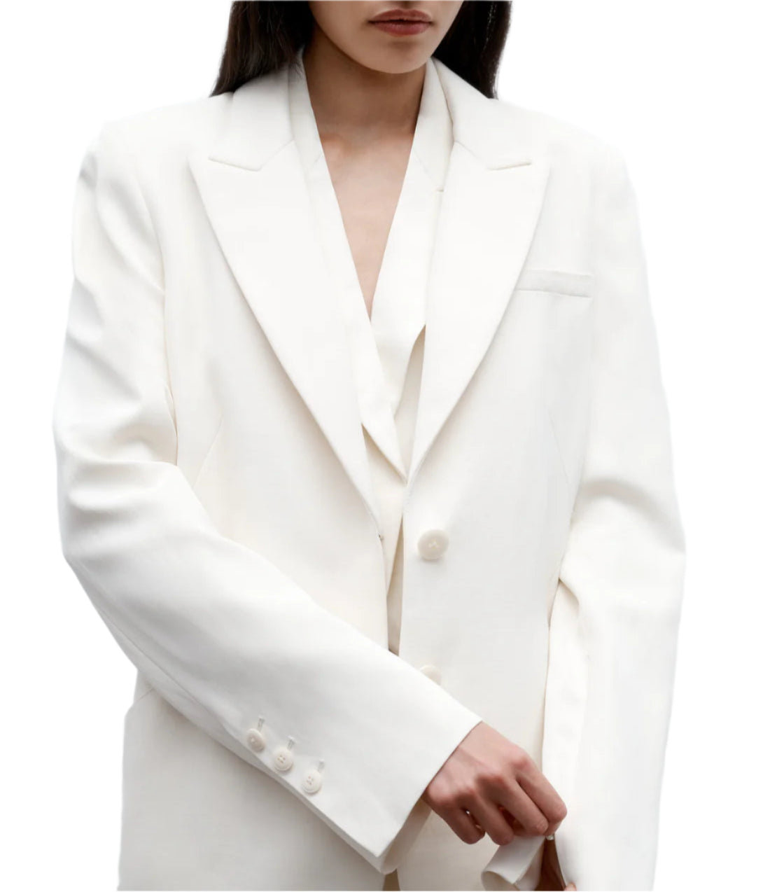 A person wearing the TWP Perfect Boyfriend Blazer—an oversized white single-breasted style with notch lapels and buttoned cuffs—stands against a white background.