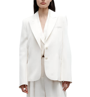 A woman wearing the TWP Perfect Boyfriend Blazer with wide-leg trousers stands against a plain white background.