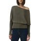 A person wears the Simkhai Lavina Draped Off Shoulder Sweater in olive-green with an asymmetric neckline, paired with dark blue jeans, standing against a plain white background.