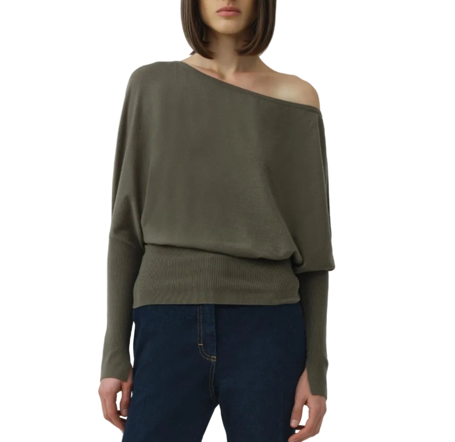 A person wears the Simkhai Lavina Draped Off Shoulder Sweater in olive-green with an asymmetric neckline, paired with dark blue jeans, standing against a plain white background.