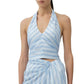 A woman is shown from shoulders to hips wearing the Simkhai Caprie Halter Top in Oxford Blue and white satin stripes, paired with a matching wrap skirt.