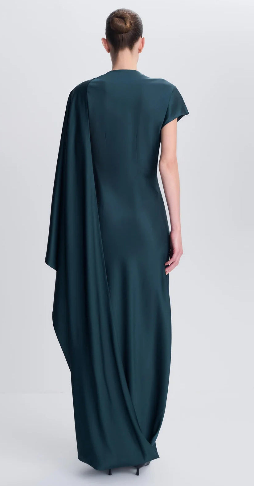 Back view of the Simkhai Ora Satin Gown, a floor-length dark green dress with an asymmetrical long sleeve and a draped panel over one shoulder.