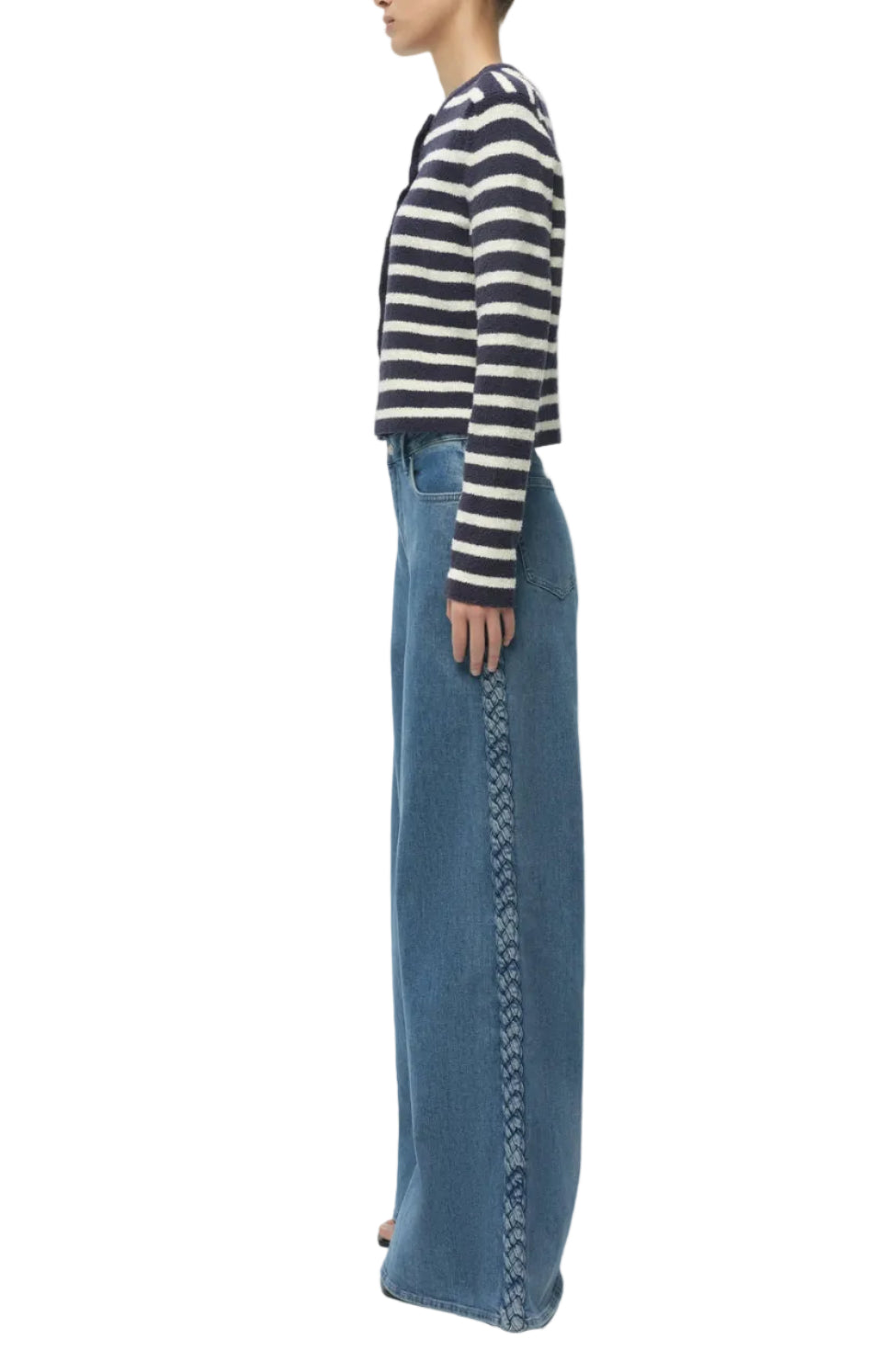 A person stands sideways wearing a navy and white striped sweater and Simkhai’s Booker Straight Jean—high-waisted, premium blue denim with braided detailing and classic 5-pocket construction.
