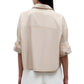 A woman is seen from the back wearing TWP's Next Ex Vintage Washed Poplin, a loose-fitting, collared shirt with rolled-up sleeves, paired with white pants.