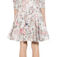 A person wearing the Prabal Gurung Mini Shirtdress, featuring a fashionable floral pattern with three-quarter sleeves and a flared skirt, effortlessly blending style and comfort. They are paired with high-heeled shoes and facing away from the camera.