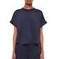 A person wears the Simkhai Addy Satin T-Shirt, featuring a relaxed fit, short sleeves, and a round neckline in navy blue, paired with matching pants, shown waist up against a plain background.
