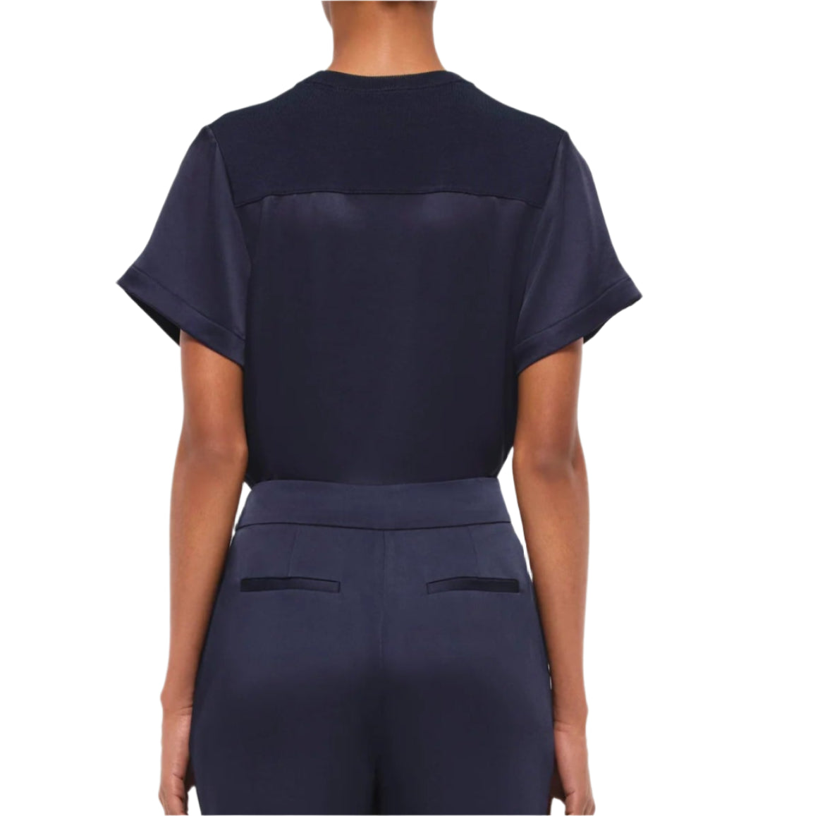 A woman is seen from behind wearing the Simkhai Addy Satin T-Shirt in navy, featuring a relaxed fit and short sleeves, paired with matching navy pants with welt pockets, set against a plain white background.