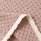Close-up of pink perforated knit fabric with a scalloped white trim, evoking the delicate detailing found on Rylee & Cru’s Girls’ Pointelle Knit Pant, which features a scalloped hem; one corner is folded over to reveal both sides of the material.