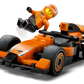LEGO® City F1® Driver with McLaren Race Car by Legos - Toyhouse features an orange and black F1 toy car with a smiling minifigure in an orange suit and helmet, posed as if leaping from the Formula 1 vehicle.