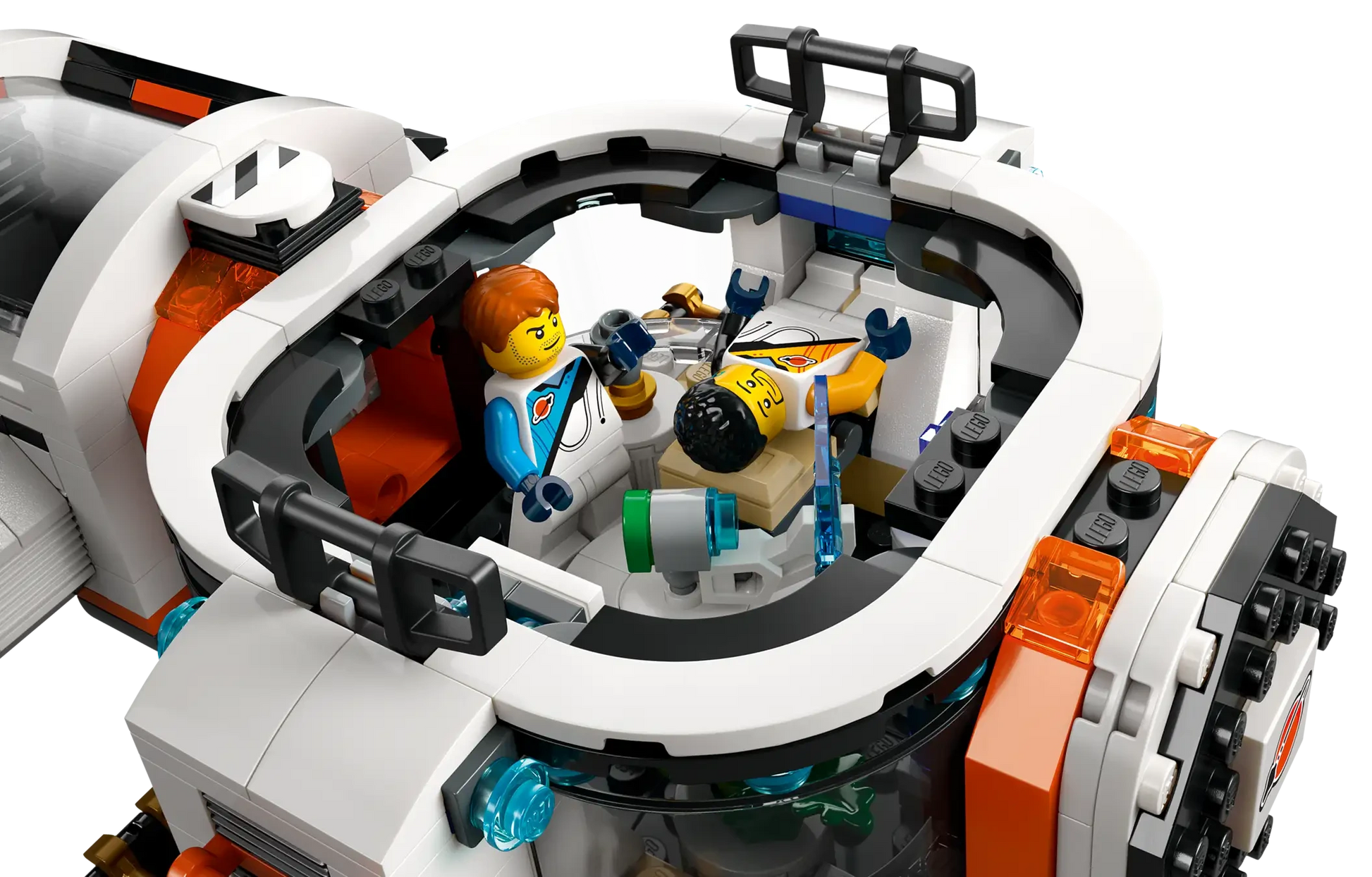 Two LEGO astronaut minifigures are in the white and orange cockpit of the LEGO® City Modular Galactic Spaceship by Legos - Toyhouse, with one sitting and the other reclining in a control chair.