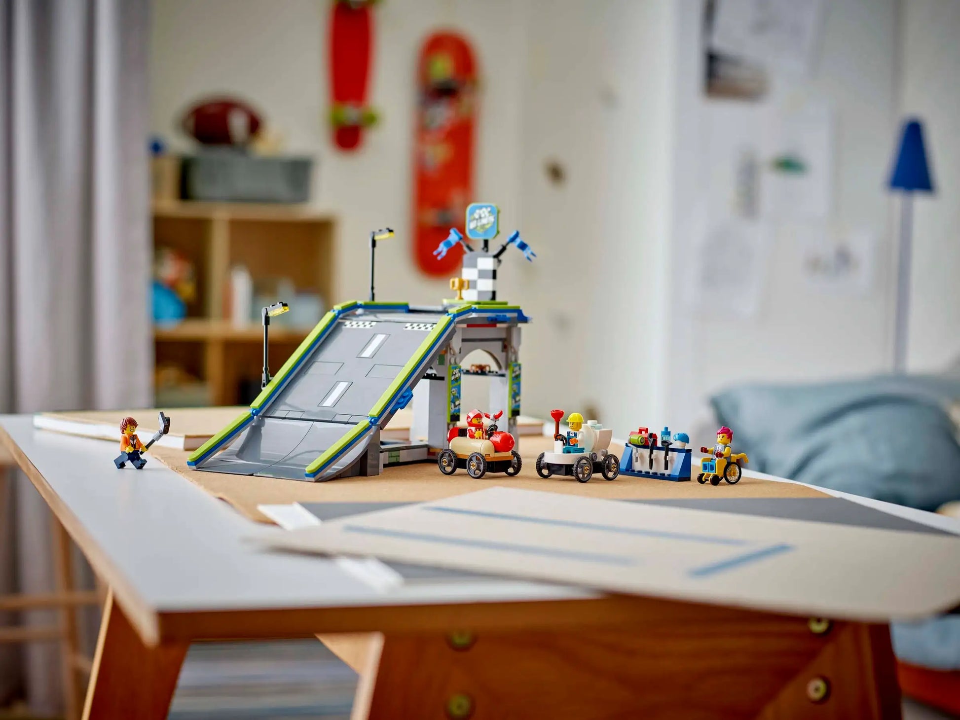 A LEGO® City No Limits: Race Car Ramp Track by Legos - Toyhouse is set up with stunt vehicles on a table in a child’s bedroom, with shelves and toys in the background.