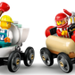 Two LEGO minifigures race on the LEGO® City No Limits: Race Car Ramp Track by Legos - Toyhouse—one in a construction helmet with a plunger, the other in a red helmet driving a sausage-shaped car, wrench in hand.