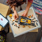 A person assembles the LEGO® City Yellow Bulldozer by Legos - Toyhouse on a tray, with building toy pieces and an iPad showing instructions nearby.