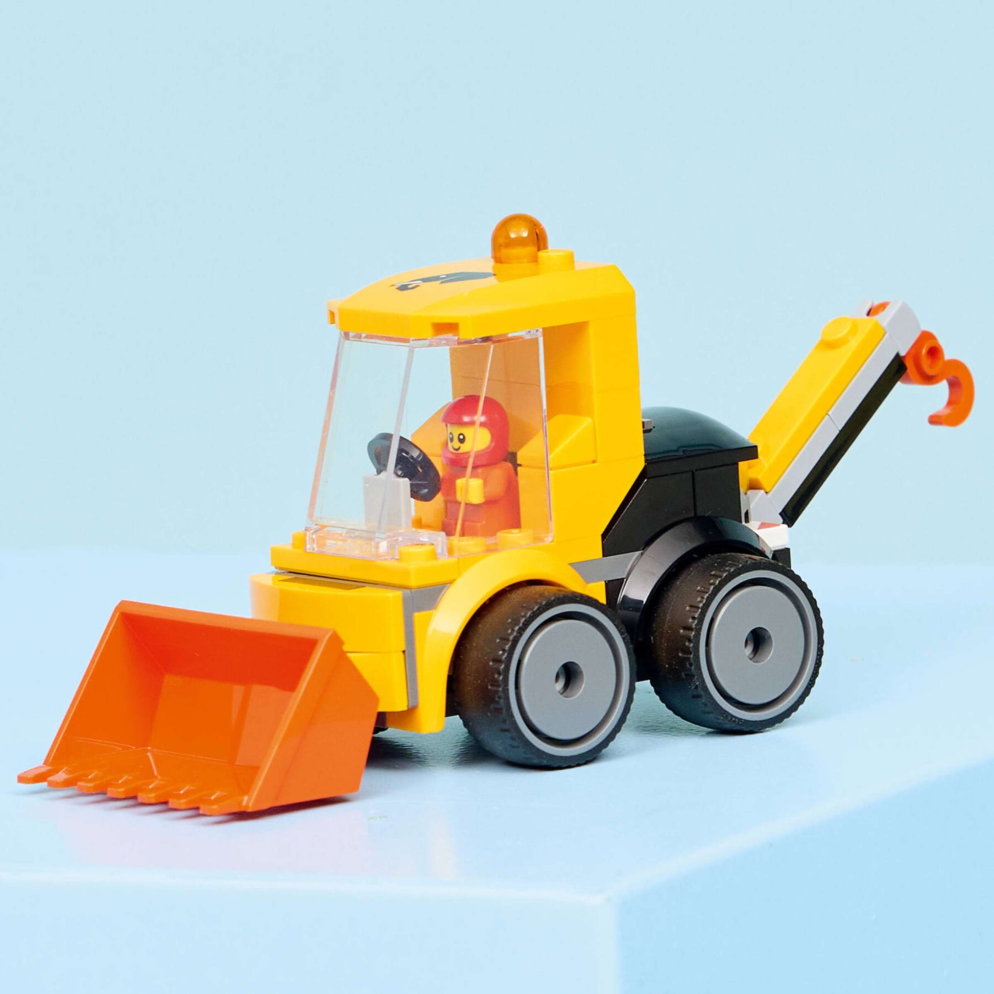 The LEGO® City Rides – Construction Loader by Legos - Toyhouse features a yellow loader with an orange scoop, a hook, and a driver mini-figure—an ideal addition to any kids’ building kit.