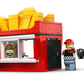 LEGO minifigures stand by the LEGO® City Fries Food Truck from Legos - Toyhouse, a red fries stand shaped like a box of fries with a fries sign and a black and white food truck toy in the background.