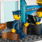 Three LEGO figures in a modern office—one in sunglasses with a briefcase, another at a computer, and one near a croissant by the window—a fun scene inspired by Legos - Toyhouse's LEGO® City Airport with Airplane for airport toy fans.