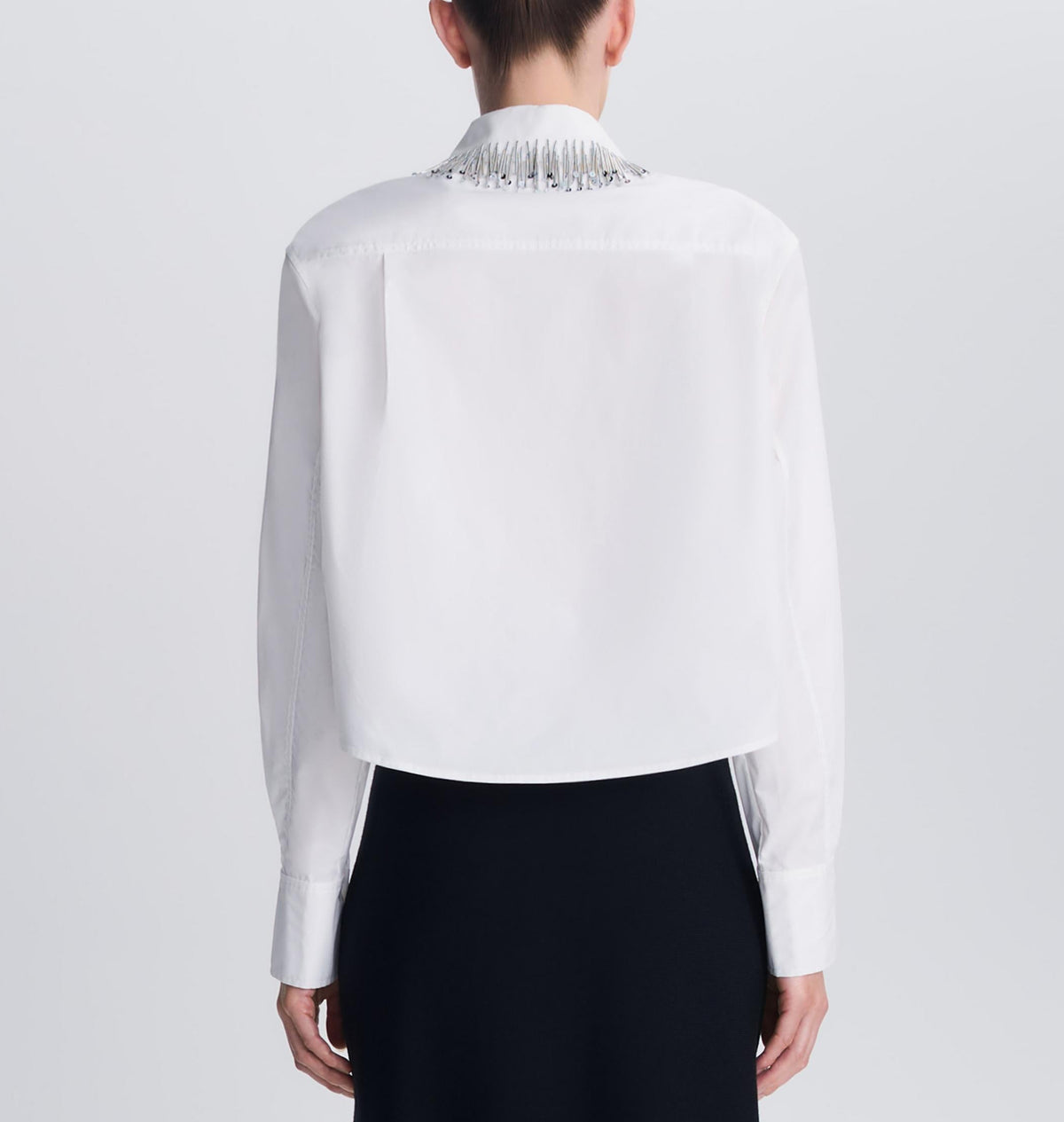 Back view of a white cotton poplin Renata Embellished Collar Cropped Shirt with long sleeves and metallic fringe embellishment on the back of the collar.