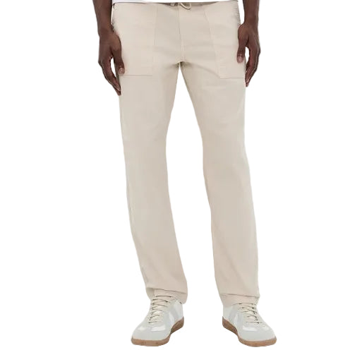 A person wearing the Faherty Dune Utility Pant, featuring garment-dyed stretch twill and an elastic waistband, paired with white sneakers and standing against a plain background.