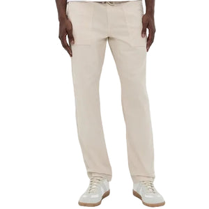 A person wearing the Faherty Dune Utility Pant, featuring garment-dyed stretch twill and an elastic waistband, paired with white sneakers and standing against a plain background.