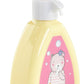 A hand presses the top of a yellow bottle with a pink label featuring a cartoon bear and "Corolle," part of the Corolle Floral Changing Accessories Set—ideal for your doll accessories or imaginative play on the go.