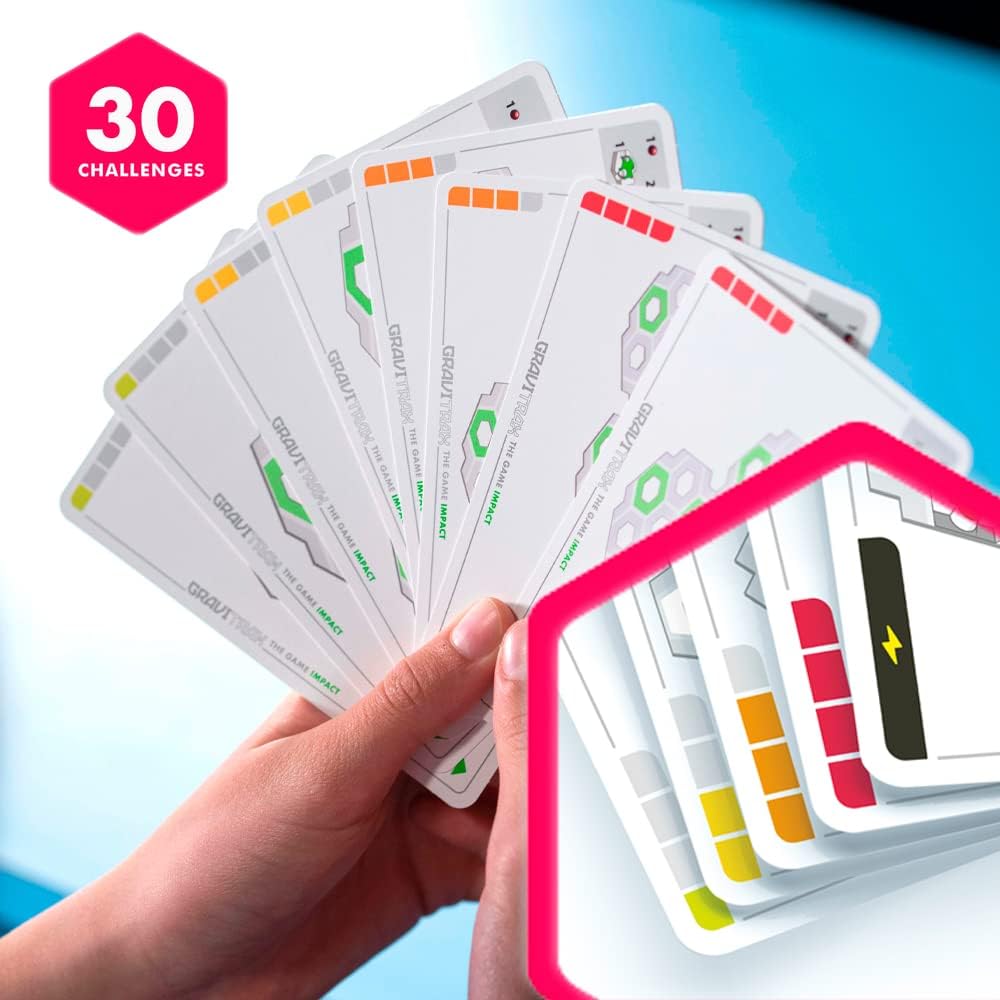 A hand displays fanned-out GraviTrax: The Game Course cards with colorful bars and icons, beside a pink "30 challenges" badge on a blue background—ideal for GraviTrax fans or any STEM toy enthusiast.