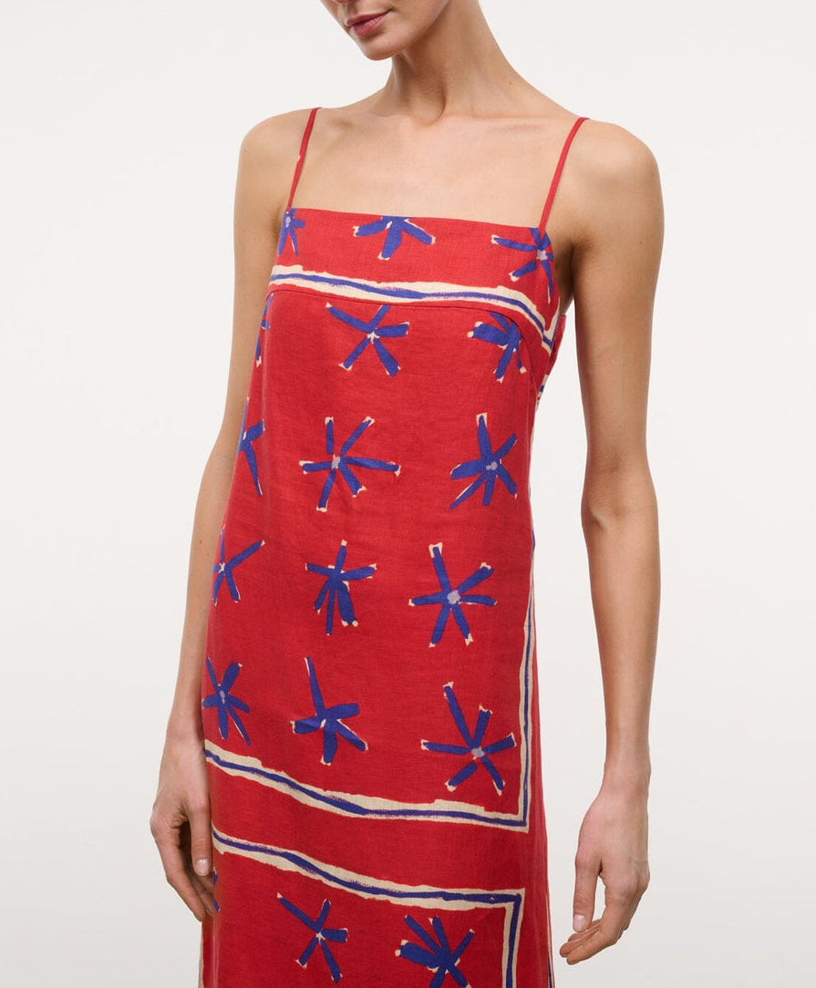 A person wearing the Laura Linen Maxi Dress by Staud, featuring adjustable spaghetti straps and a blue and white abstract star pattern.