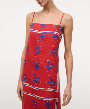 A person wearing the Laura Linen Maxi Dress by Staud, featuring adjustable spaghetti straps and a blue and white abstract star pattern.
