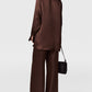 A person wearing a Stella McCartney Star Silk Jacquard Shirt with wide-leg dark brown trousers, carrying a small black shoulder bag.