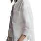 Person wearing a relaxed fit, loose-fitting white cotton TWP Day After Top and matching pants, with hands in pockets, on a white background.